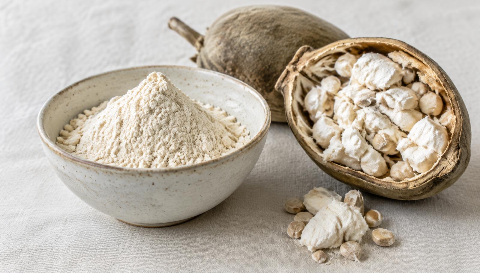 Poudre de baobab dans un bol à côté d'un fruit de baobab ouvert